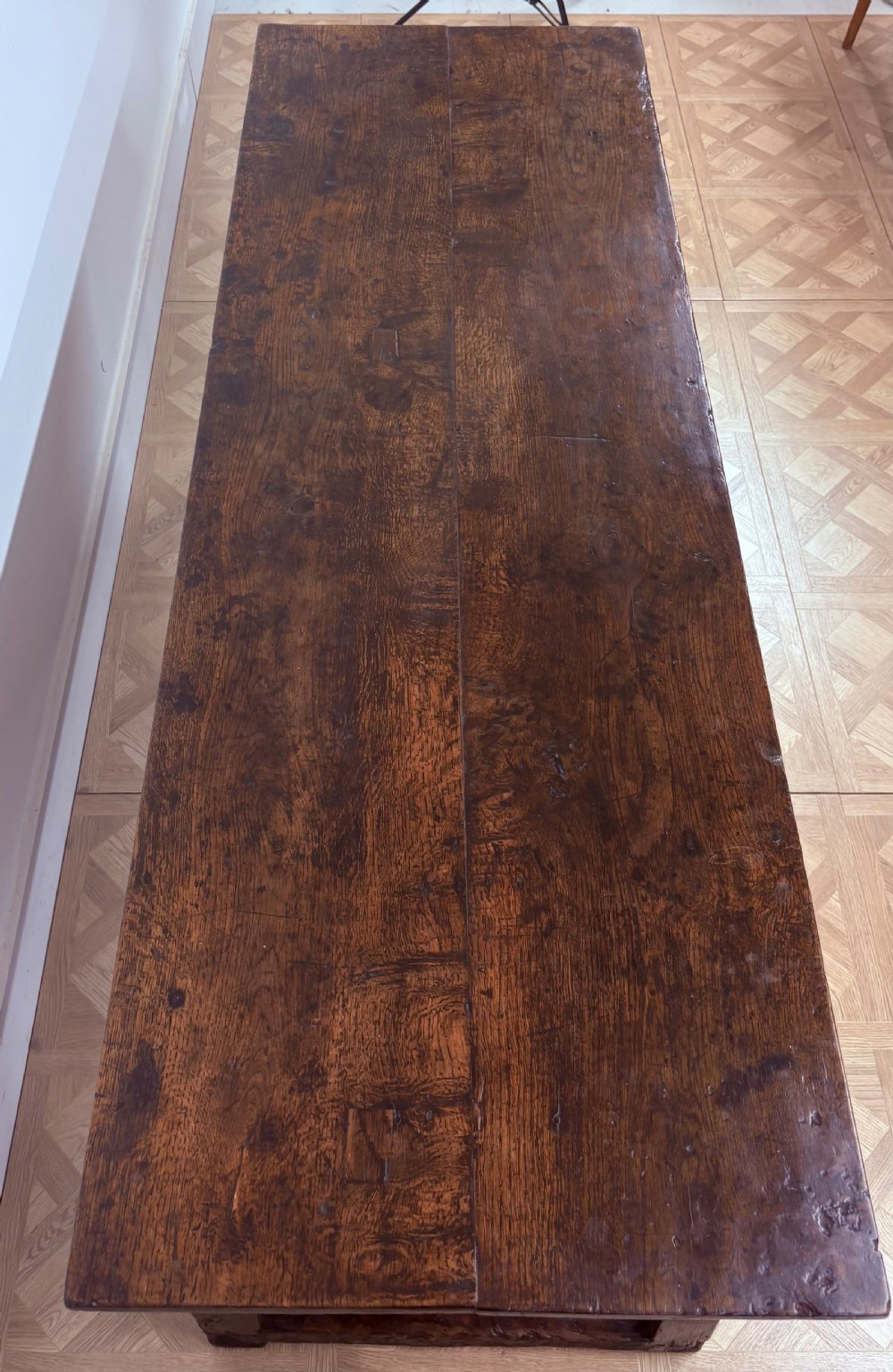 A dark oak refectory dining table paired with six matching carved wooden dining chairs set on a parquet floor. View V