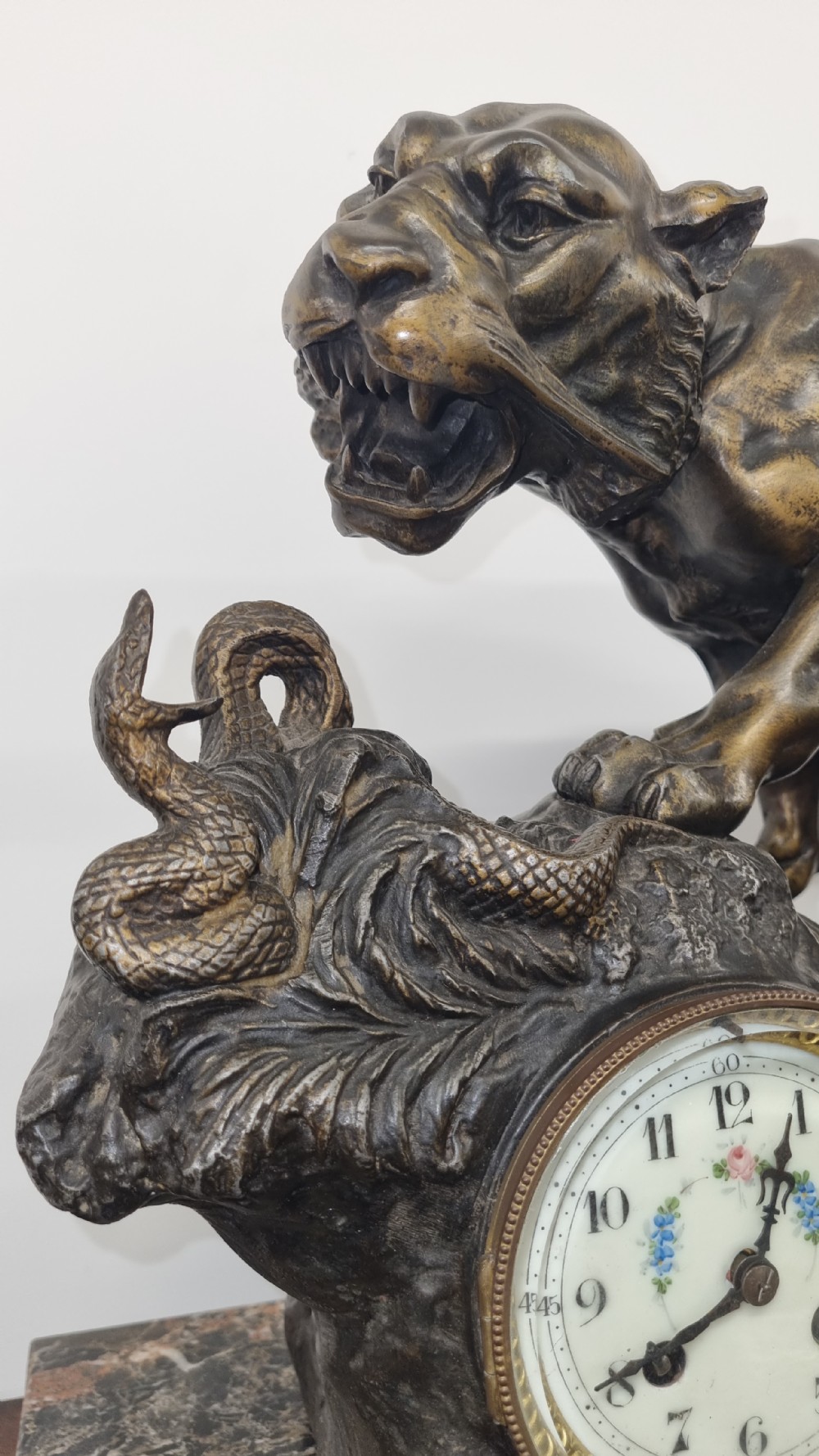 A dark patinated bronze sculpture of a tiger fighting a serpent set upon a rock housing a round clock dial, all resting on a rectangular veined marble base. View VII