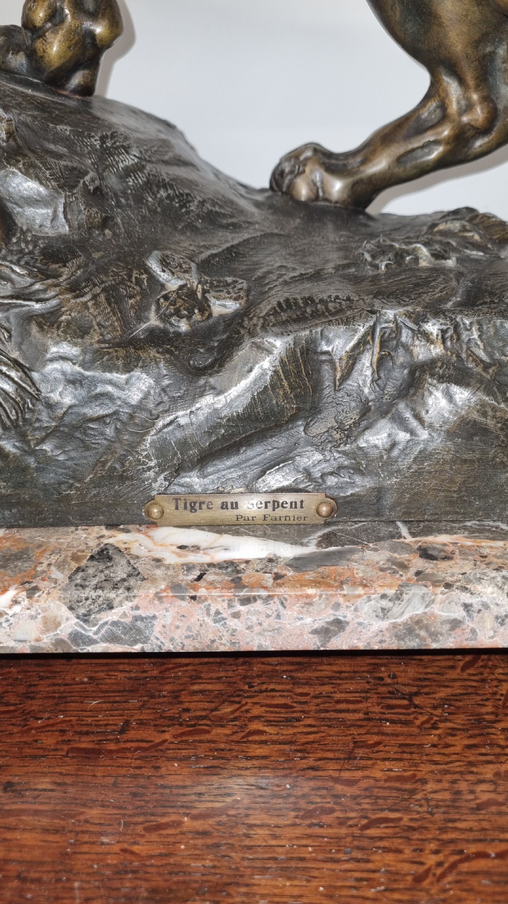 A dark patinated bronze sculpture of a tiger fighting a serpent set upon a rock housing a round clock dial, all resting on a rectangular veined marble base. View VIII