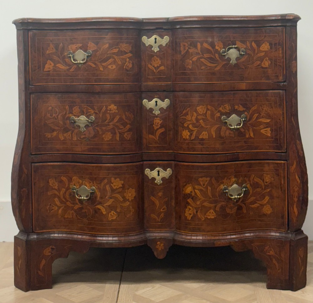 An eighteenth-century Dutch walnut chest of drawers featuring shaped drawer fronts with detailed floral marquetry inlays and decorative brass escutcheons. View II