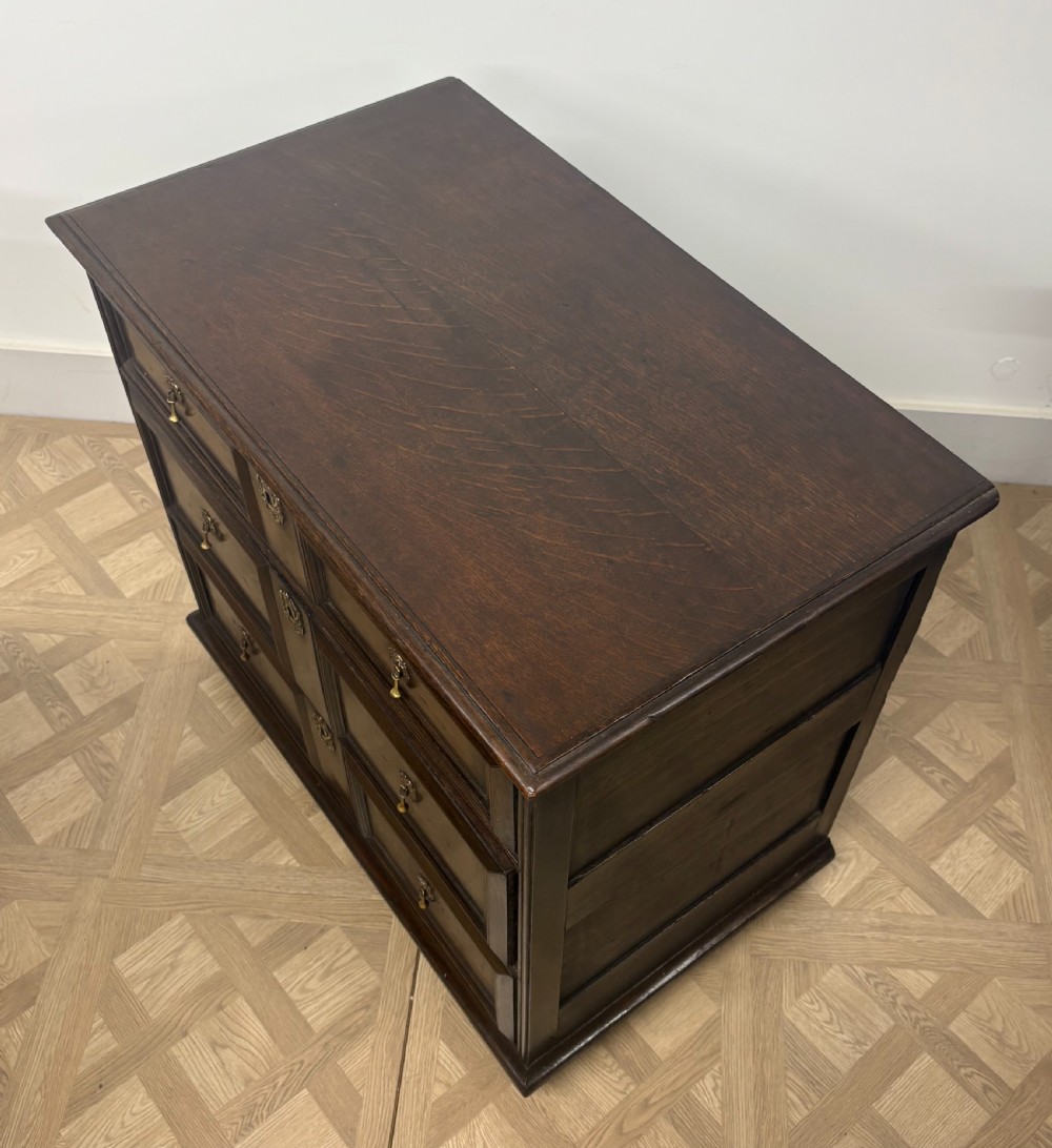 A seventeenth-century Charles II dark oak chest of drawers featuring three drawers with geometric moulded fronts and brass teardrop handles. View III