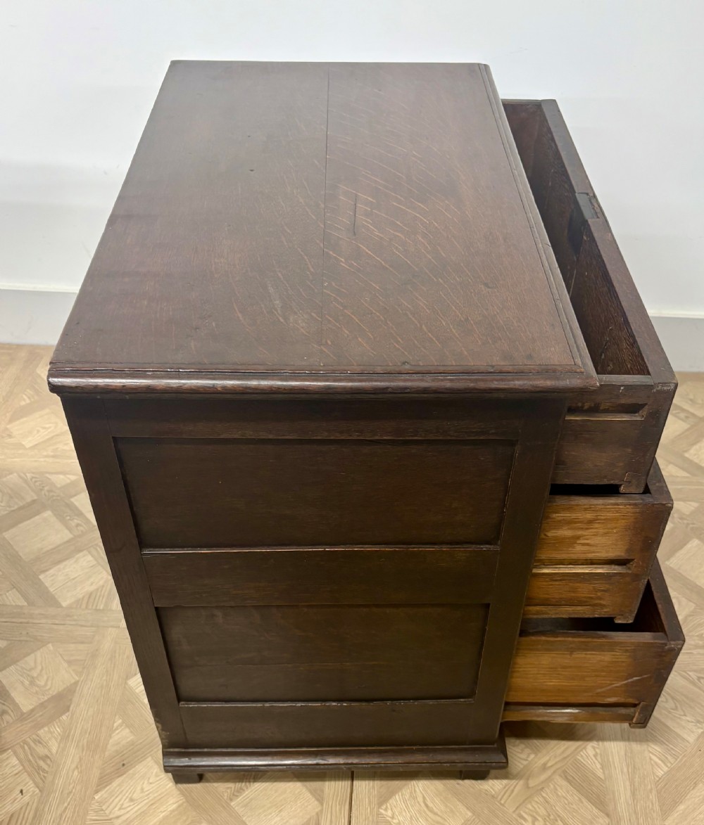 A seventeenth-century Charles II dark oak chest of drawers featuring three drawers with geometric moulded fronts and brass teardrop handles. View V