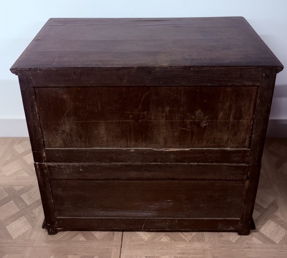 A seventeenth-century dark oak chest of drawers featuring geometric applied mouldings, bobbin detailing, and brass drop handles. View V
