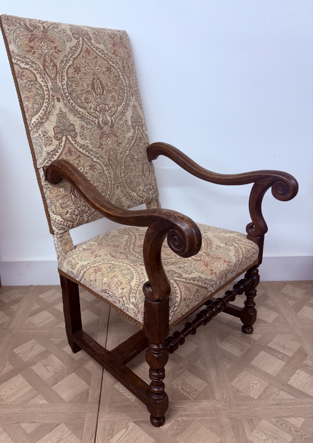 A late 17th-century French walnut armchair featuring a tall patterned fabric backrest, curved scroll arms, and turned legs with stretchers. View II