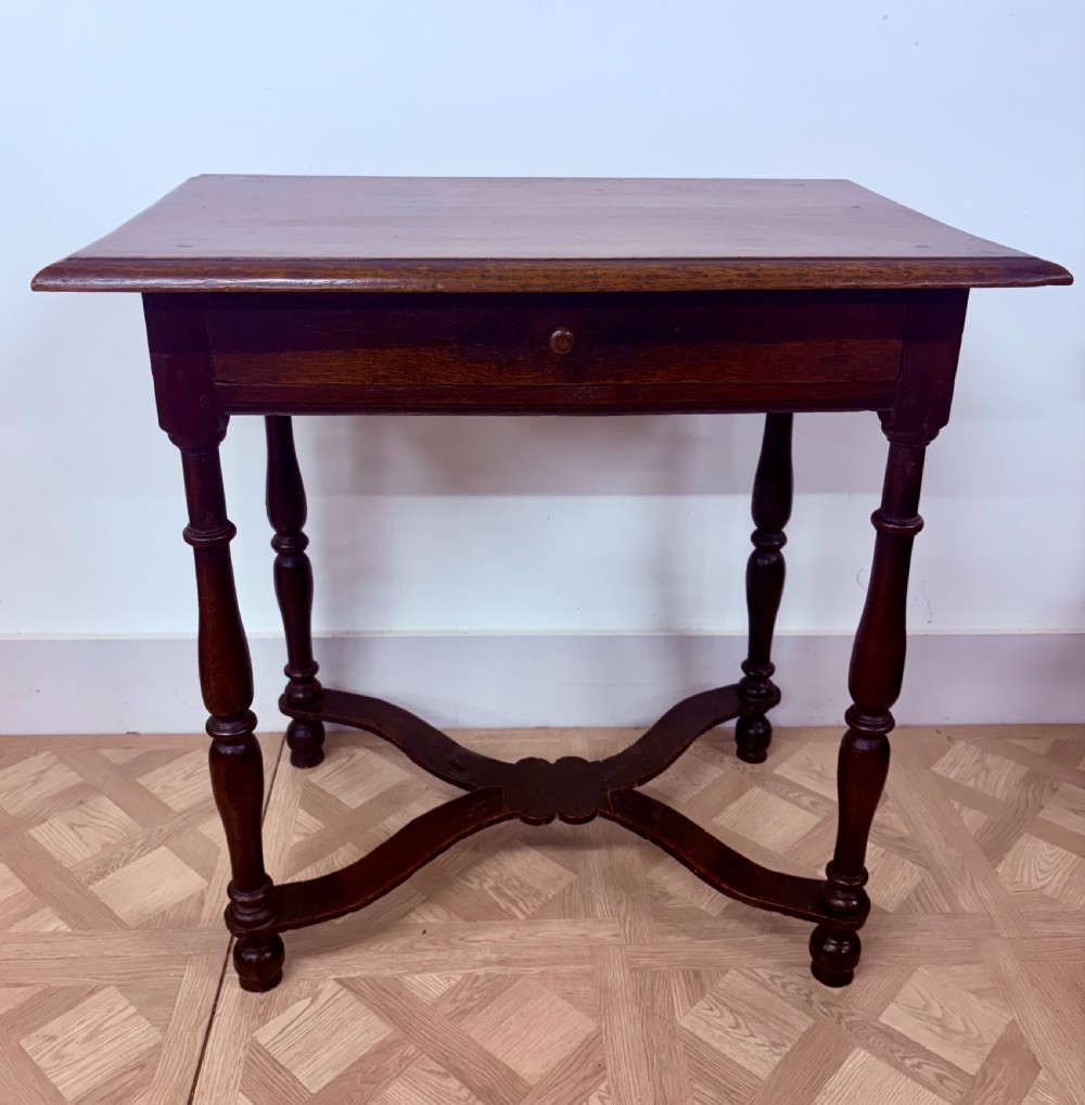 A late 17th-century dark oak side table with turned legs, a single frieze drawer, and a shaped X-frame stretcher. View II
