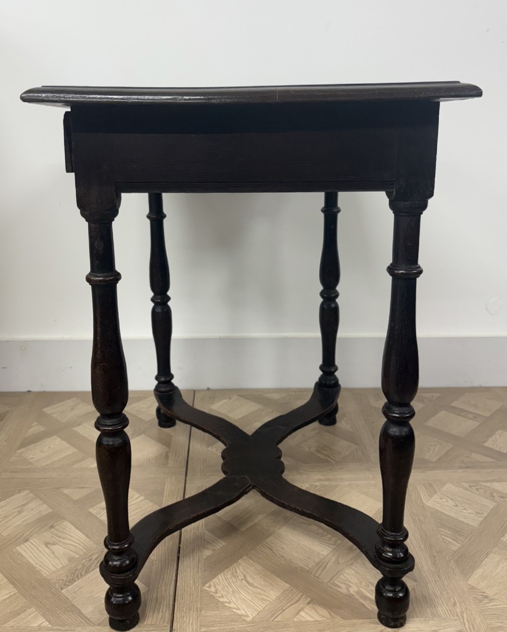 A late 17th-century dark oak side table with turned legs, a single frieze drawer, and a shaped X-frame stretcher. View V