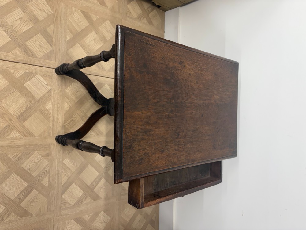 A late 17th-century dark oak side table with turned legs, a single frieze drawer, and a shaped X-frame stretcher. View VI