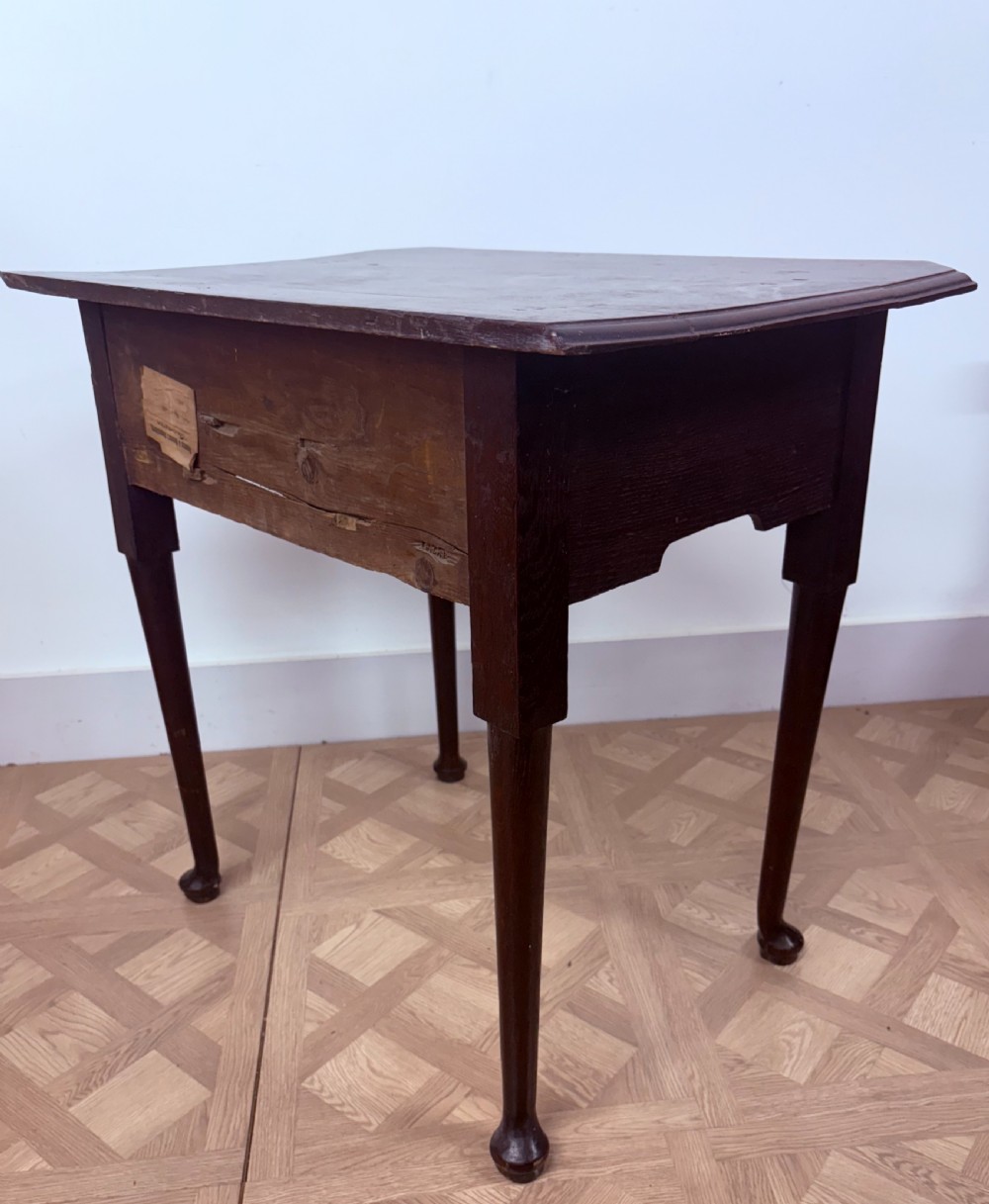 An early 18th-century dark oak side table featuring three drawers with brass ring pulls, a scalloped apron, and slender cabriole legs ending in pad feet. View V