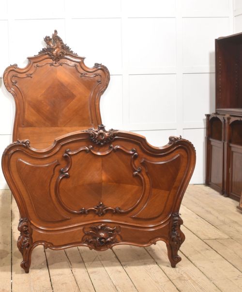 fig 1. A matching pair of carved walnut single bed frames with high crest headboards, serpentine footboards, and book-matched timber panels.