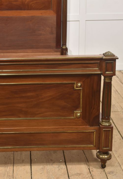 fig 1. Late nineteenth-century mahogany bedframe featuring brass mouldings, fluted post columns topped with pineapple finials, and raised panel work on the headboard and footboard.