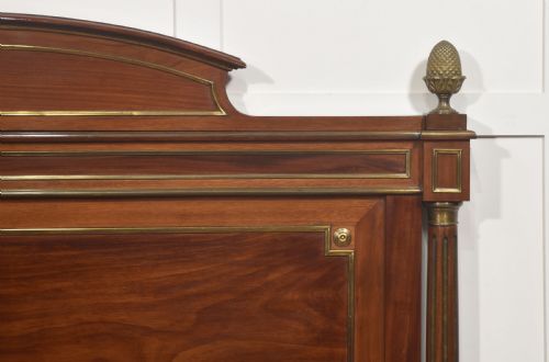 fig 2. Late nineteenth-century mahogany bedframe featuring brass mouldings, fluted post columns topped with pineapple finials, and raised panel work on the headboard and footboard.