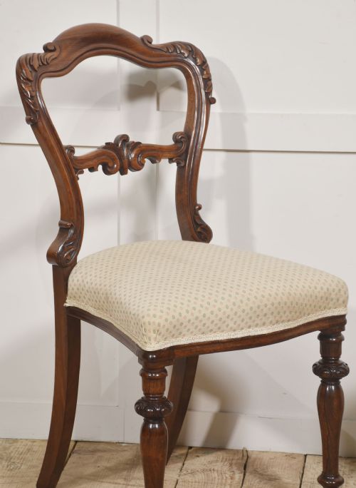 fig 1. A pair of mid-19th-century rosewood side chairs featuring open balloon backs with carved detail rails, turned front legs, and cream-coloured patterned fabric seats.