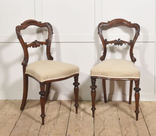 fig 2. A pair of mid-19th-century rosewood side chairs featuring open balloon backs with carved detail rails, turned front legs, and cream-coloured patterned fabric seats.