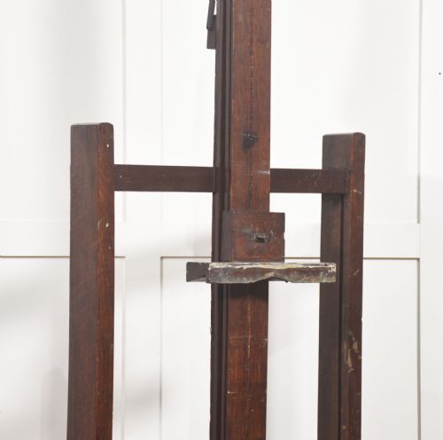 fig 1. A tall dark oak adjustable artists studio easel featuring a hand-crank winding mechanism and castors.