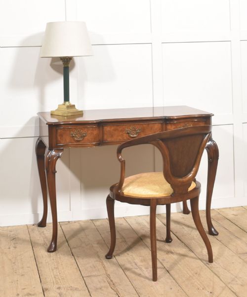 fig 1. A burr walnut writing table featuring three drawers with brass handles and slender cabriole legs.