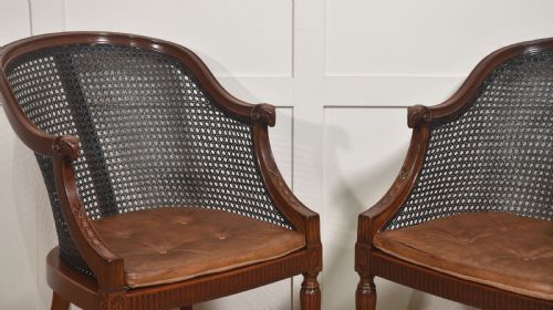 fig 1. A pair of Regency style dark mahogany bergere armchairs featuring woven cane backs and tan leather buttoned seat cushions.
