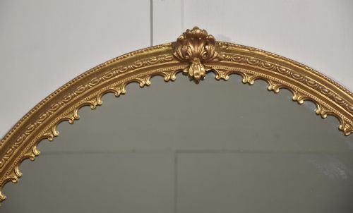 fig 1. A large 19th-century oval wall mirror featuring a gilded frame with top shell cresting and scalloped inner detailing.