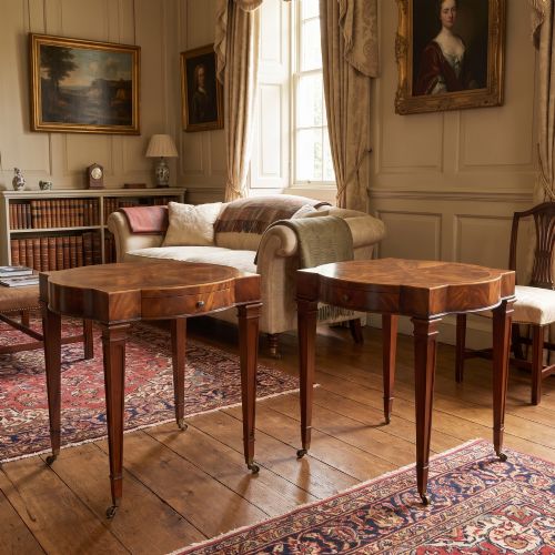 fig 1. A pair of mahogany Sheraton Revival side tables featuring shaped inlaid tops, single frieze drawers, fluted tapered legs, and brass castors.
