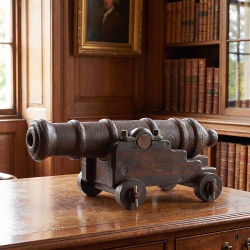 fig 1. A nineteenth-century cast-iron signal cannon with a dark patina, mounted on a stepped dark oak carriage with wooden wheels.