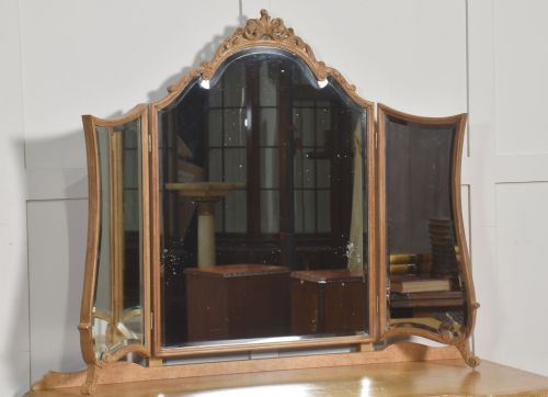 fig 2. A light burr walnut dressing table featuring five drawers, brass handles, carved cabriole legs, a three-piece folding mirror, and a matching upholstered stool.