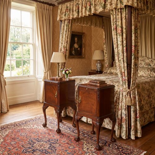 fig 1. A pair of warm brown mahogany Chippendale style bedside cabinets featuring carved cabriole legs ending in ball and claw feet, flame mahogany single door cupboards, brass drop handles, and pull-out brush slides.