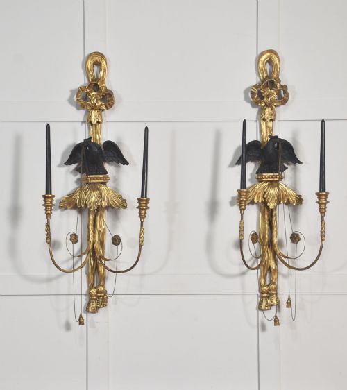 fig 1. A pair of George III style giltwood wall sconces featuring carved ribbon crestings, dark eagle motifs, and twin candle arms.