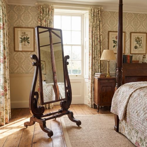 fig 1. A William IV mahogany cheval mirror featuring carved scroll upright supports, a tilting full-length rectangular glass frame, and a stretcher base with swept feet.