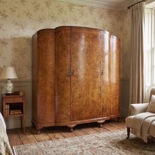 fig 1. An Art Deco burr walnut breakfront wardrobe with curved side doors, a raised central door, and short carved feet.