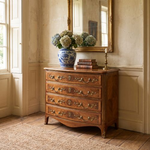 fig 1. A French Louis XV style serpentine chest of drawers featuring geometric wood marquetry and decorative brass handles.