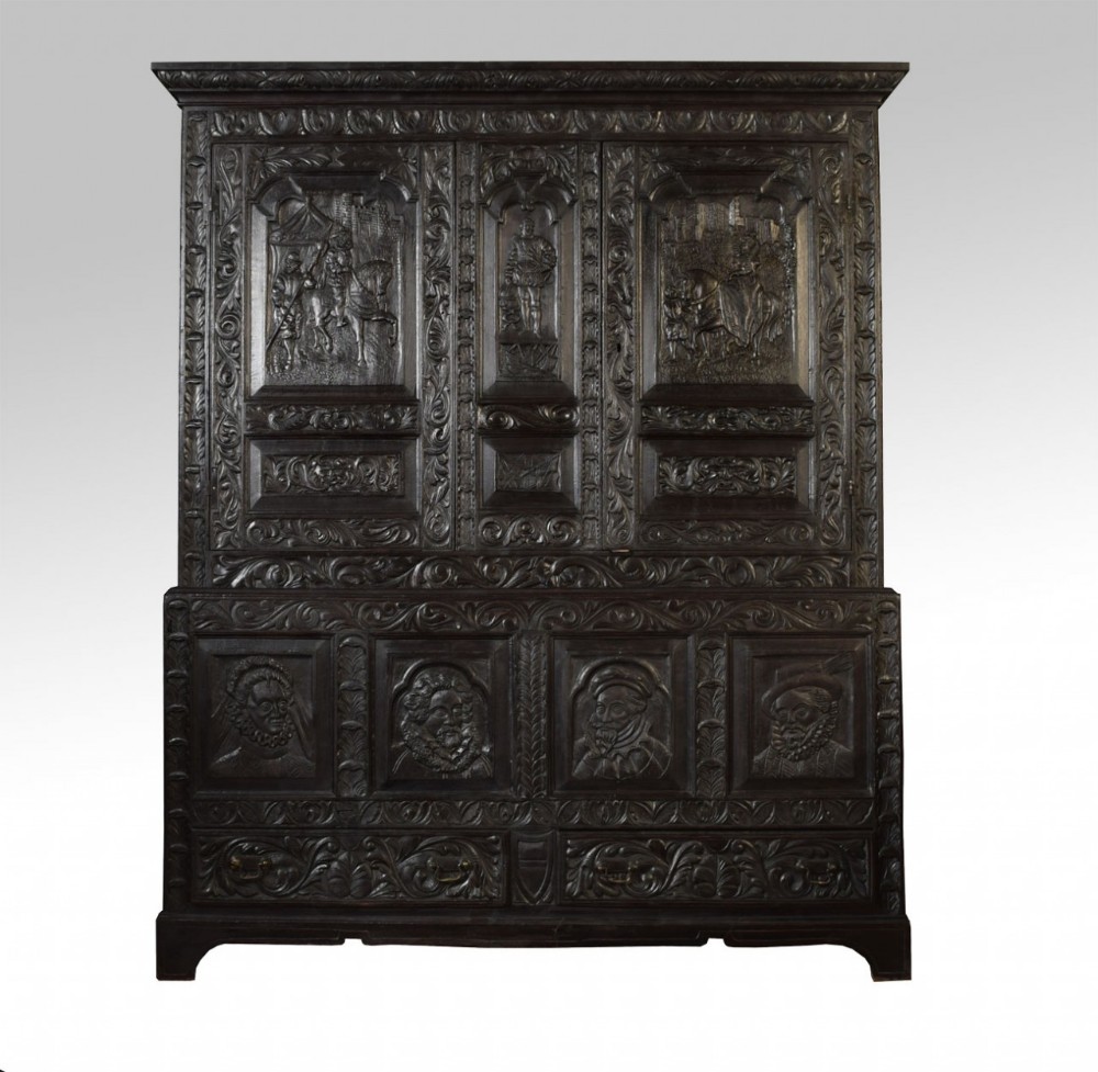Fine old oak press cupboard profusely carved with titled scenes from the court of queen Elizabeth the 1st