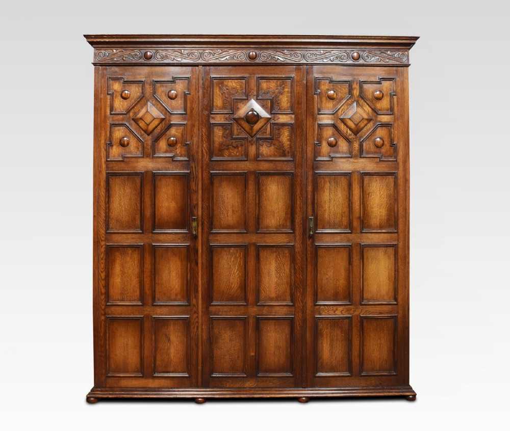 Jacobean style carved oak three door wardrobe