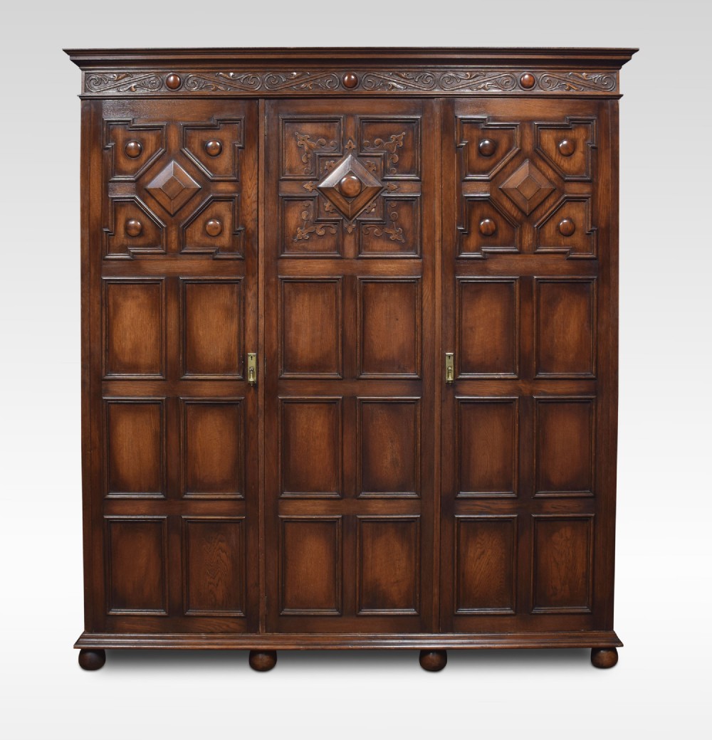 Jacobean style carved oak three door wardrobe