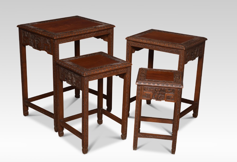 A set of four graduating Chinese hardwood nesting tables featuring relief-carved aprons and geometric borders. View III