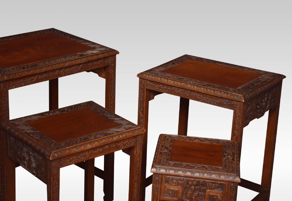 A set of four graduating Chinese hardwood nesting tables featuring relief-carved aprons and geometric borders. View IV
