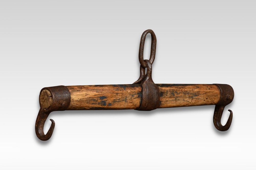 A cylindrical carved oak draught yoke featuring hand-forged wrought iron end hooks and a central iron mounting loop.