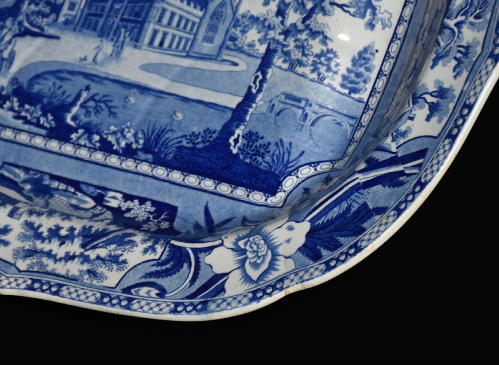 An oval 19th-century Staffordshire ceramic platter featuring a cobalt blue transfer-printed landscape scene with a stately home surrounded by intricate floral borders. View VI