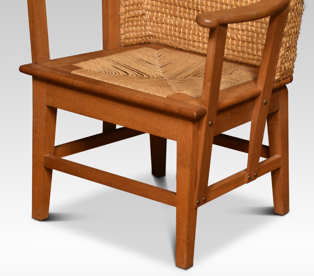 An antique oak-framed Orkney chair featuring a high curved hooded back woven from natural straw and flat timber armrests. View V