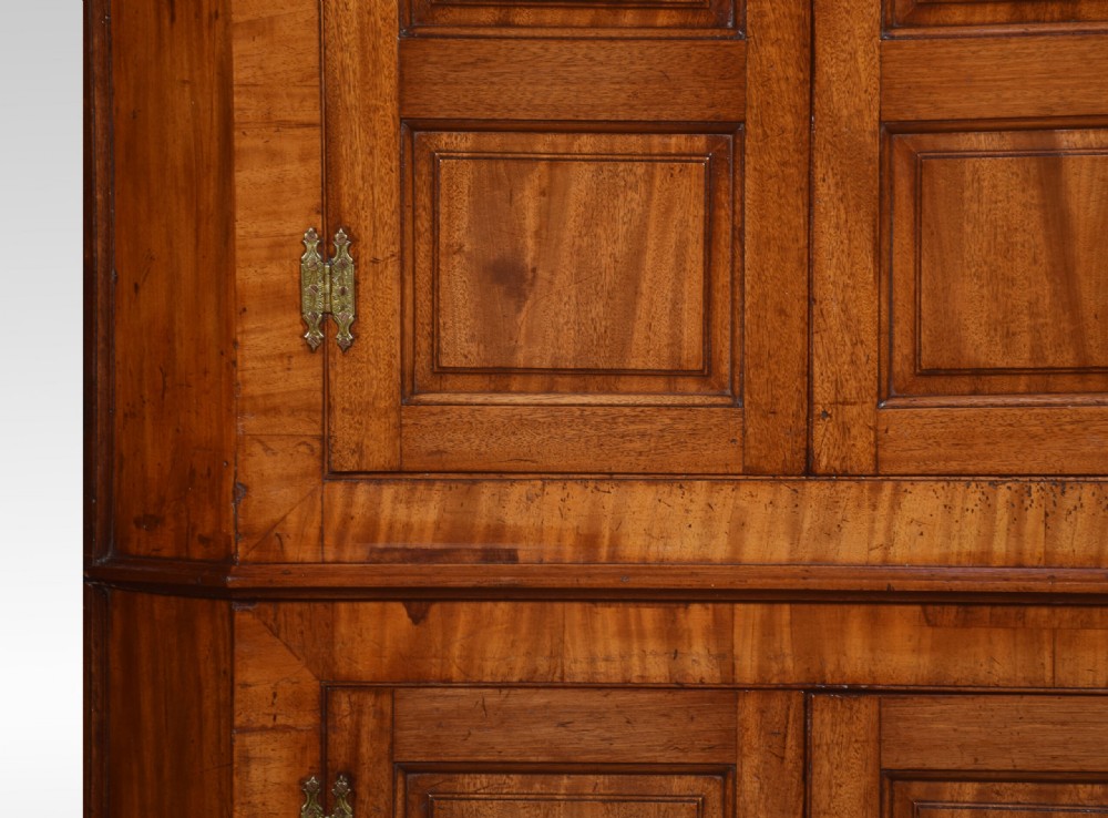 A tall, floor-standing mahogany corner cupboard with upper arched panelled doors, lower rectangular panelled doors, and brass hinges. View II