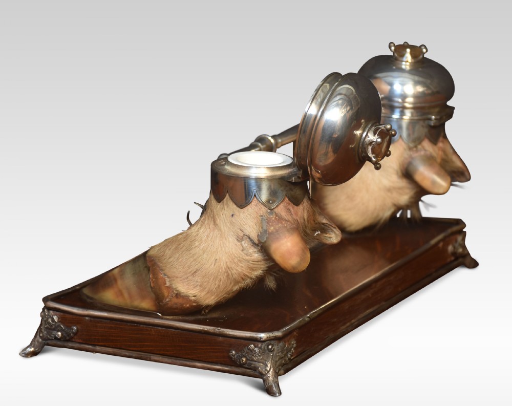 A 19th-century Scottish double inkwell set featuring two silver-capped deer hooves and stag head pen rests mounted on a mahogany base. View V