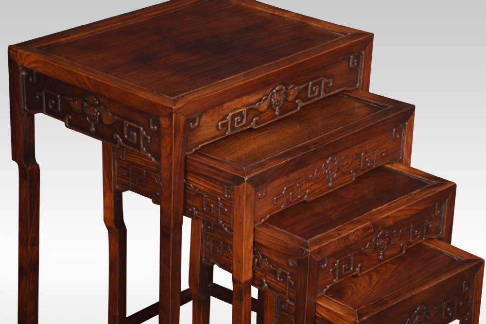 A set of four graduated dark rosewood nesting tables with carved openwork aprons and straight legs. View III