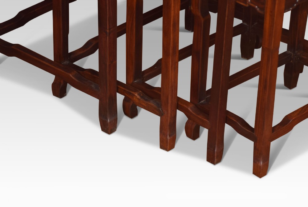 A set of four graduated dark rosewood nesting tables with carved openwork aprons and straight legs. View IV