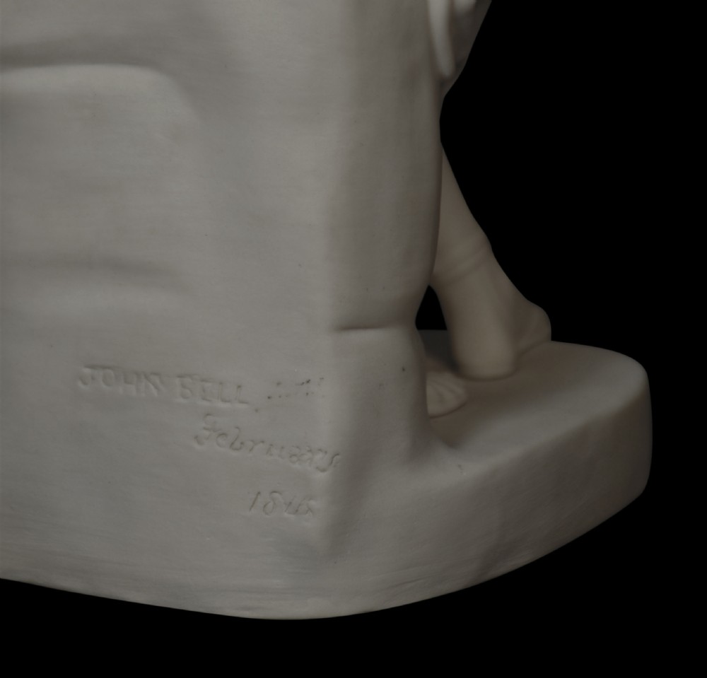 A white Parian porcelain figurine depicting a seated female warrior in detailed classical armour with a helmet resting at her feet. View VI