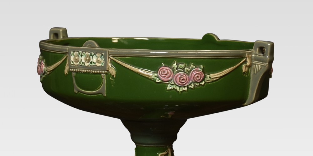 An Art Nouveau green glazed ceramic pedestal centrepiece bowl decorated with pink floral relief swags and low handles. View III