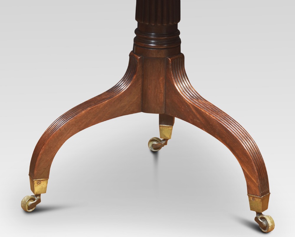 A Regency mahogany Pembroke end table featuring two drop leaves, a single frieze drawer, a reeded pedestal stem, and tripod legs with brass castors. View II