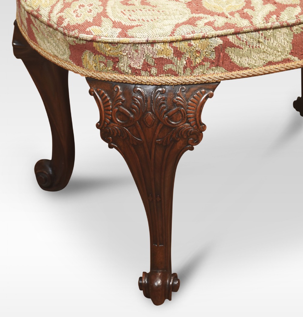 An oval George II style stool featuring patterned tapestry upholstery, carved mahogany cabriole legs, and scroll feet. View V