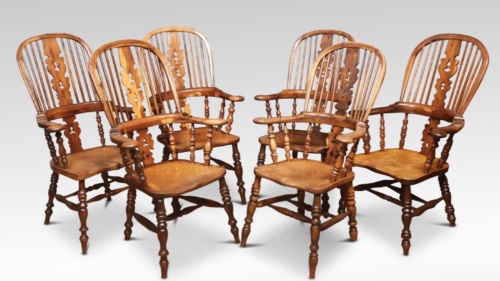 A matched set of six 19th century yew wood Windsor armchairs with pierced central splats, spindled hoop backs, and turned legs.