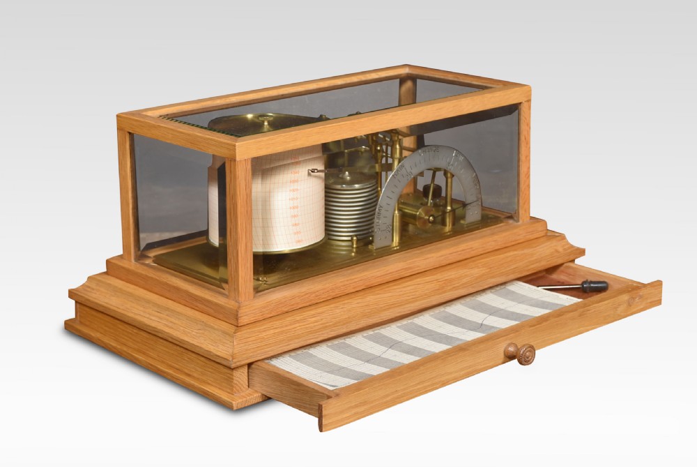 An antique oak and glass cased barograph by Negretti and Zambra featuring an internal clockwork drum, aneroid capsule stack, curved silvered scale, and base drawer. View II