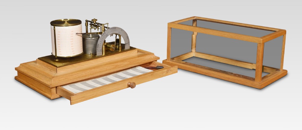An antique oak and glass cased barograph by Negretti and Zambra featuring an internal clockwork drum, aneroid capsule stack, curved silvered scale, and base drawer. View III