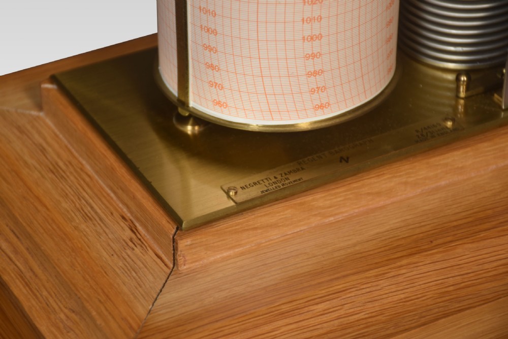 An antique oak and glass cased barograph by Negretti and Zambra featuring an internal clockwork drum, aneroid capsule stack, curved silvered scale, and base drawer. View V