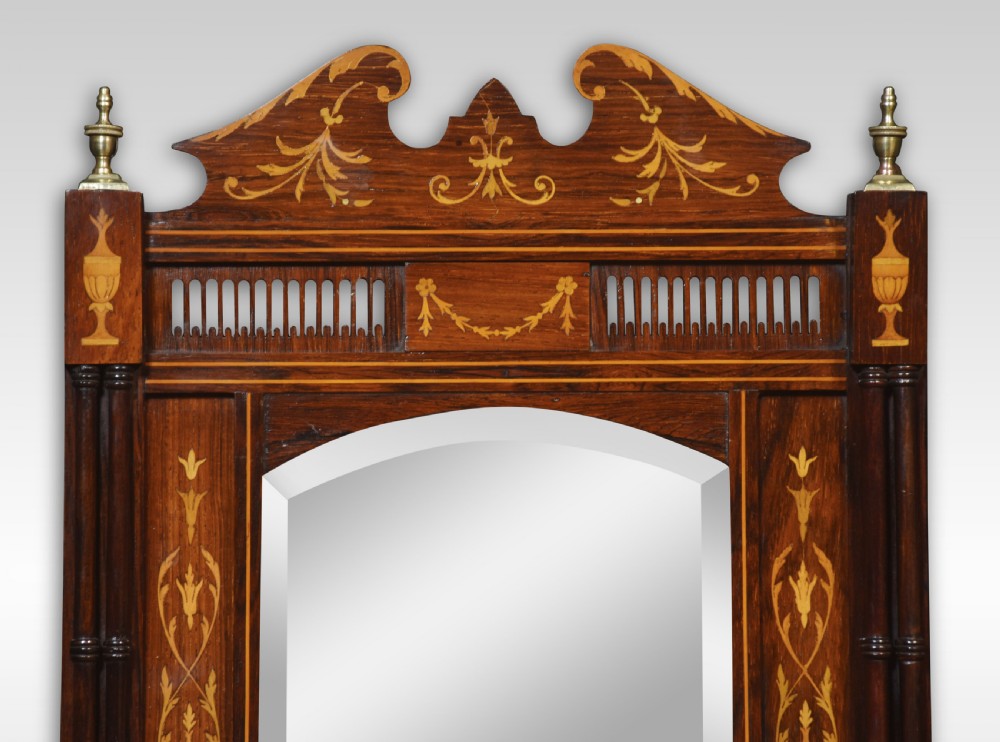 A late 19th-century dark rosewood wall mirror featuring floral and urn marquetry inlay, turned brass finials, bevelled glass, and a lower lattice fretwork shelf. View II